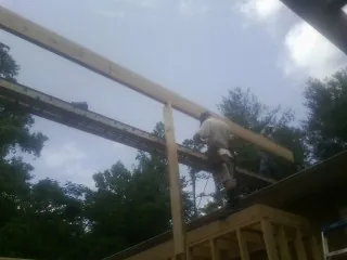 Carpenter setting a ridge beam over a new addition frame — Ice Dam Removal by Roofing Brothers in Burnt Cabins