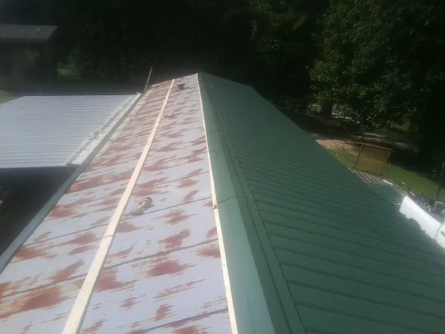Old rusted panels beside newly installed green metal roofing — Wind Damage Roof Repair by Roofing Brothers in Burnt Cabins