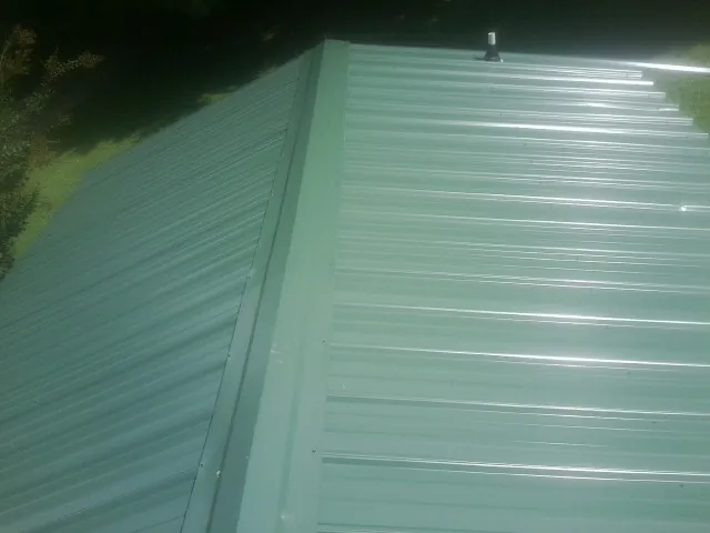 New green metal panels meeting at the ridge of a roof — Flat Roof Repair work by our crew in Burnt Cabins