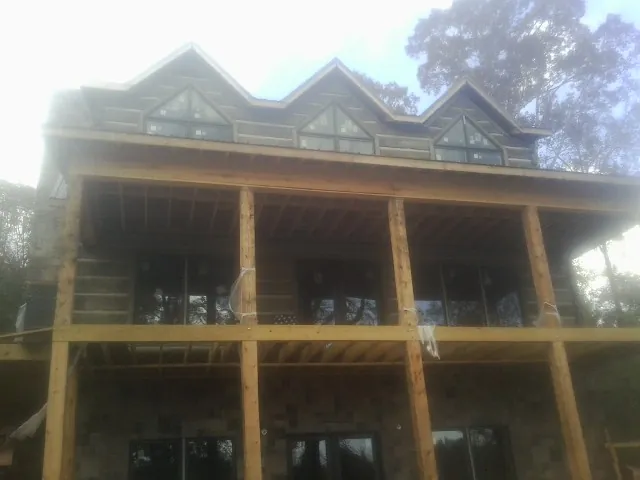 Dormers and porch framing on a large log home under construction — Roof Coating work by our crew in Burnt Cabins