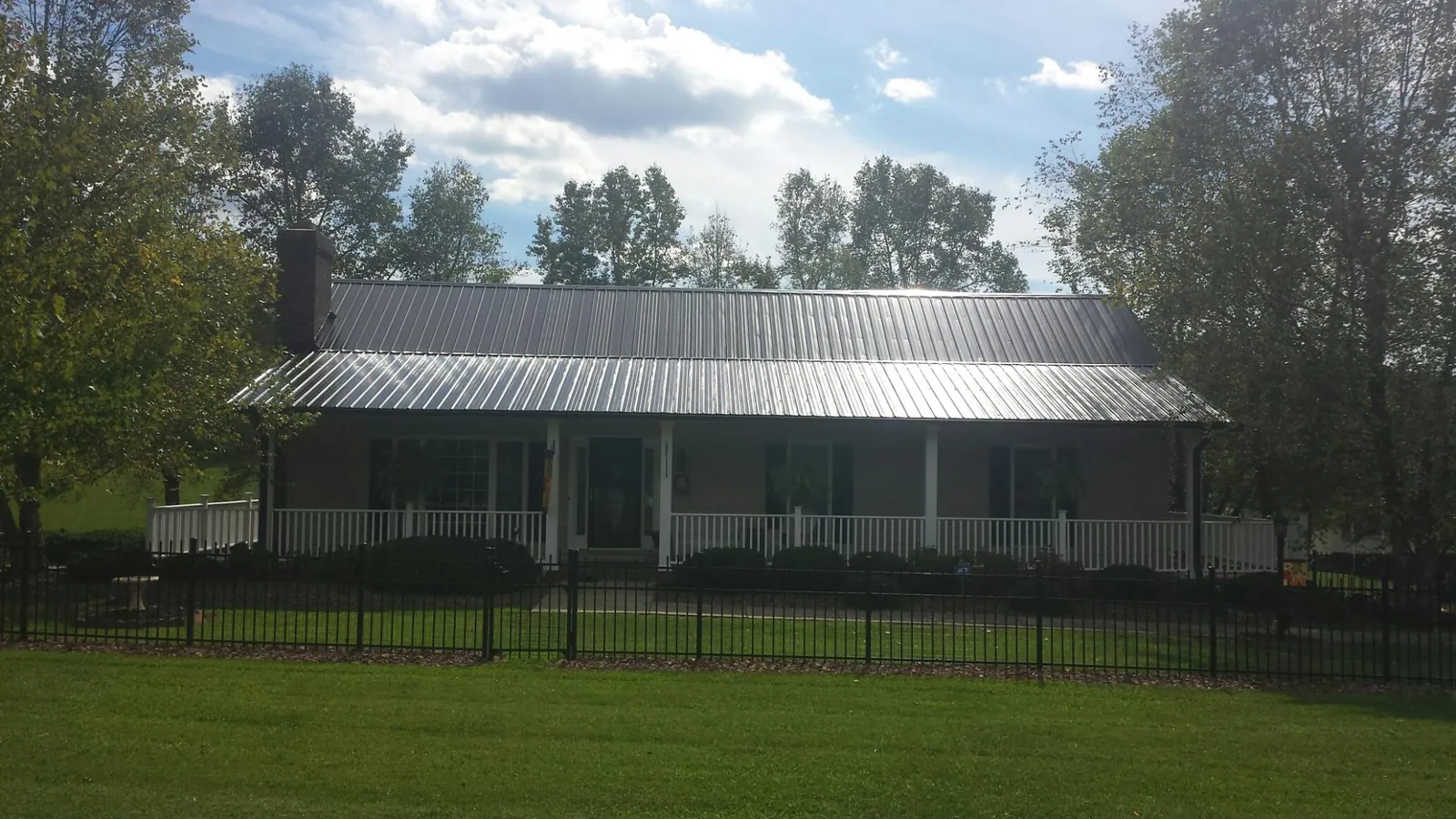 Gray metal roof on a brick ranch with a full width front porch — Gutter Guard Installation work by our crew in Burnt Cabins